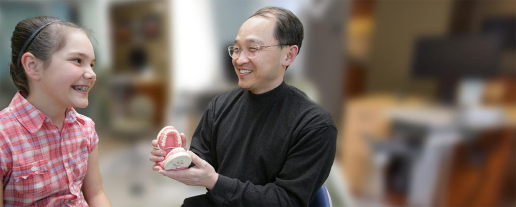 Dr. Tong showing a young girl a model of a mouth